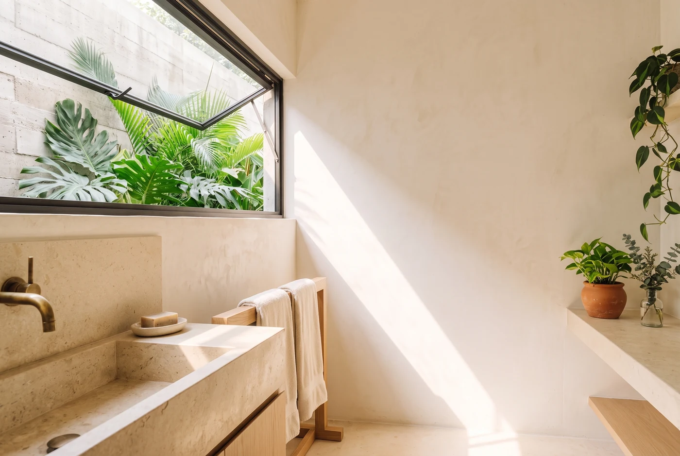 An awning window over a stone trough basin, a towel on a timber rail
